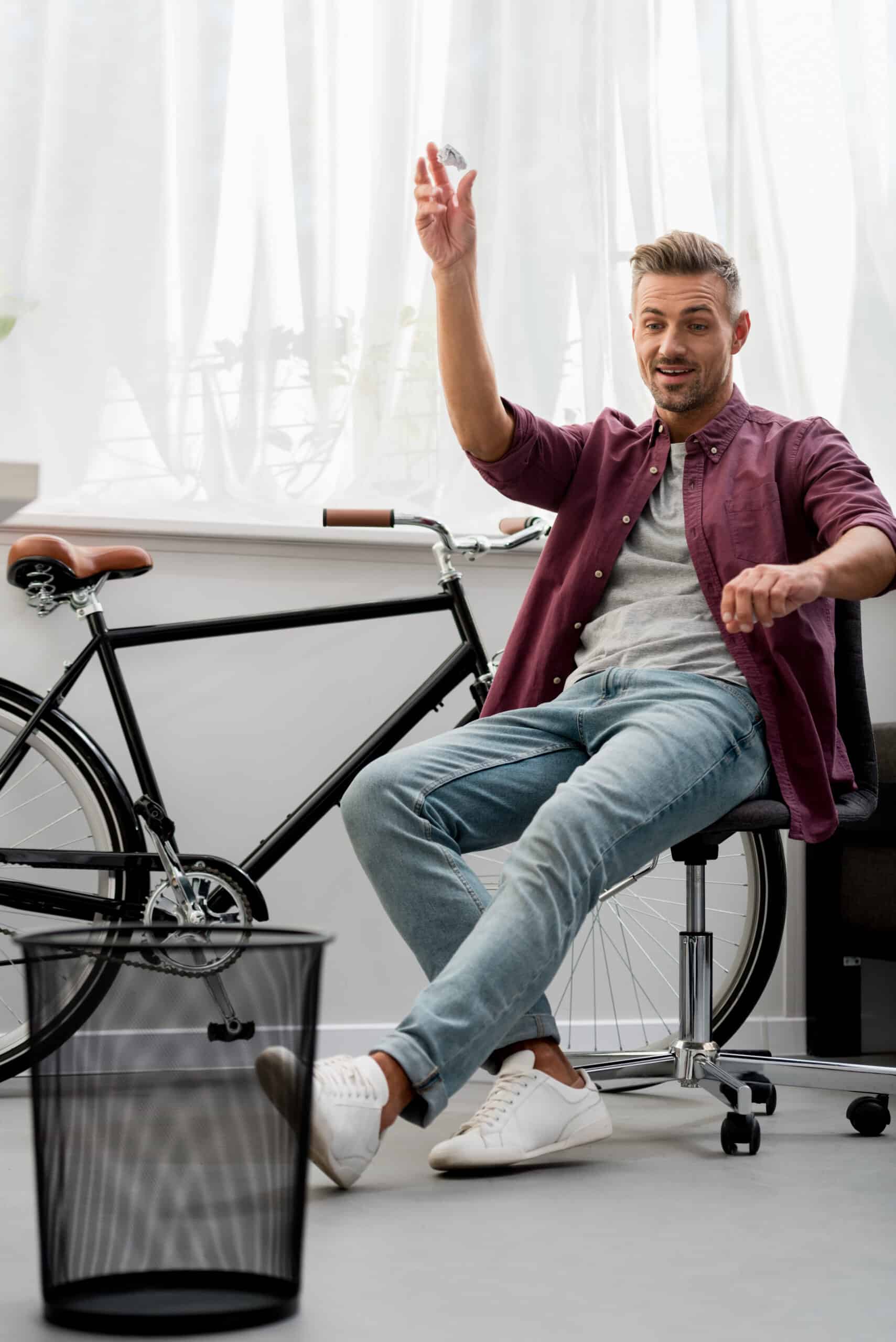 smiling adult man throwing trash in basket